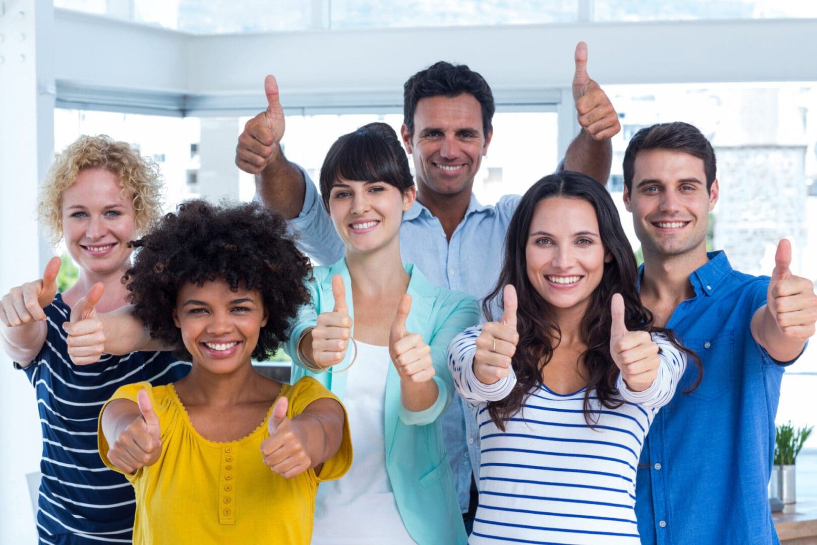 Portrait of creative team gesturing thumbs up in the office